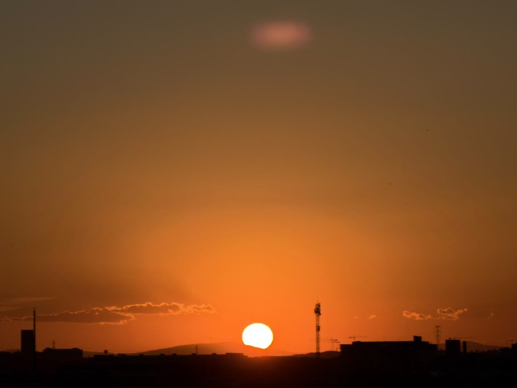 Atardecer con el sol ocultándose tras la silueta de la ciudad, evocando el relato de las nueve horas.